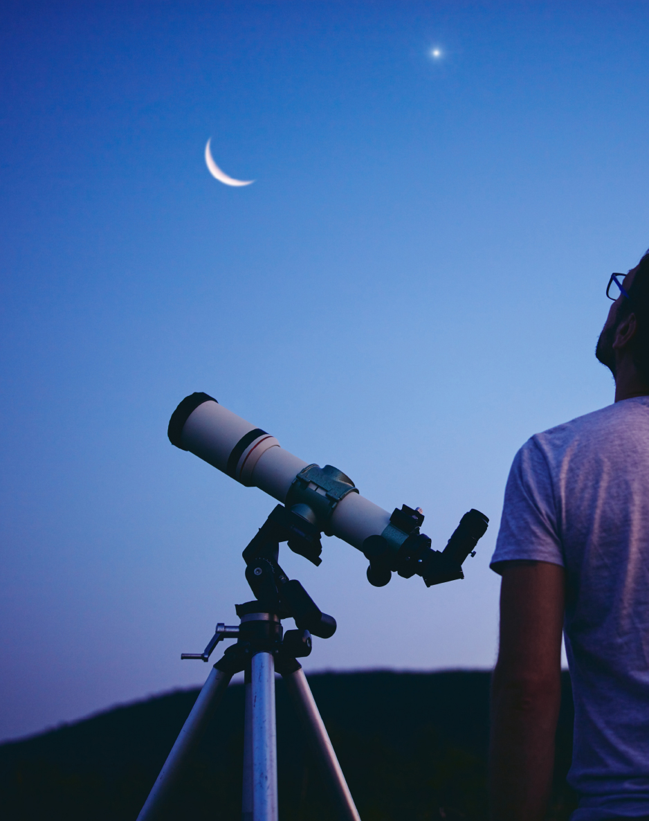 man with telescope looking at the moon